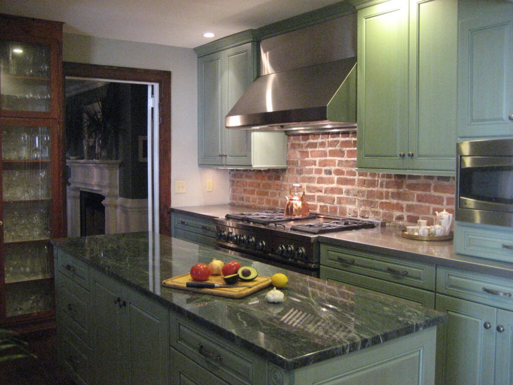 green and marble kitchen counter with silver gas range hood